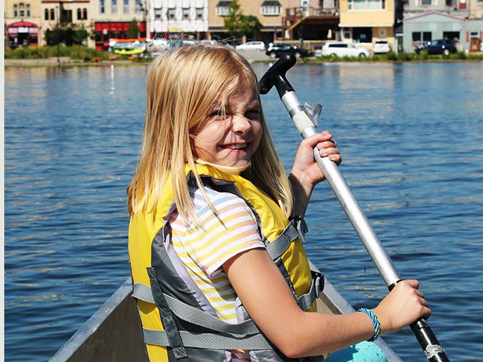 Girl wearing a yellow life jacket canoeing